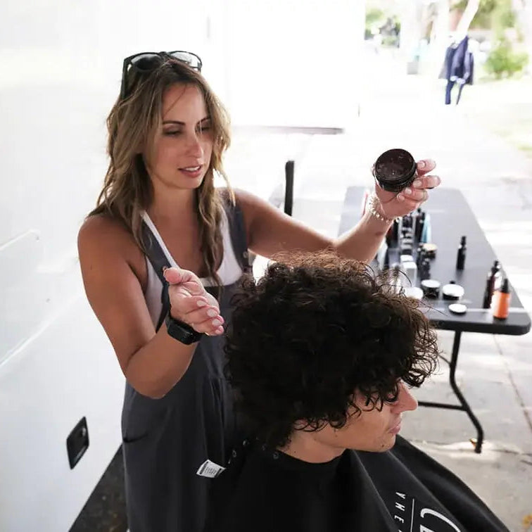 Adriana Fournier, American Crew International All-Star Stylist touches up curly hair on model Angelo before a campaign shoot.